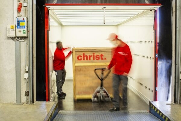 Mitarbeiter transportieren Holzkiste für Messelogistik